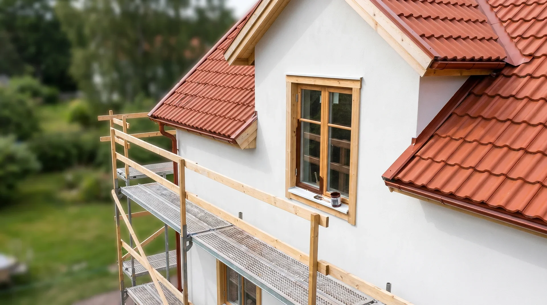 Hus under renovering med röda takpannor och byggnadsställning